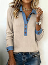 Person wearing a beige sweater with blue accents and denim shorts on a light background