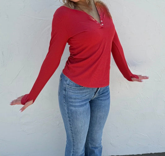 Person wearing a red long-sleeve top and blue jeans against a white background