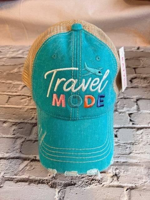 Turquoise cap with 'Travel Mode' text on a brick wall background