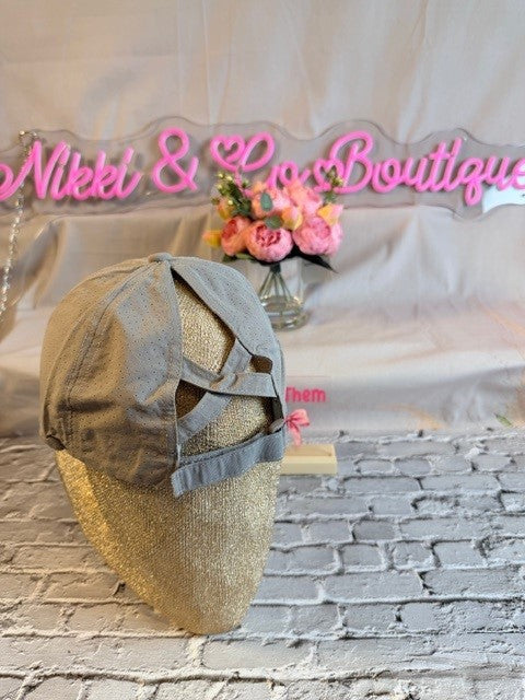 Mannequin head with a hat on a textured surface with 'Nikki & Co Boutique' sign in the background.