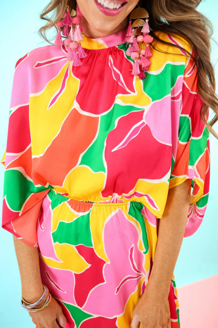 Person wearing a colorful floral dress with a bright background