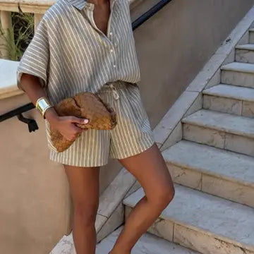 Person wearing a striped shirt and shorts holding a clutch on stone steps.
