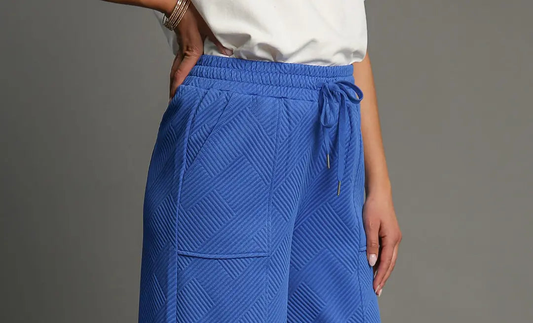 Blue textured pants worn by a person on a gray background