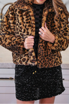 Woman wearing a leopard print jacket in a kitchen setting