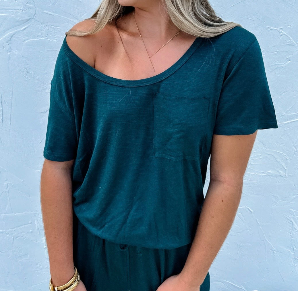 Person wearing a teal t-shirt against a light blue textured wall