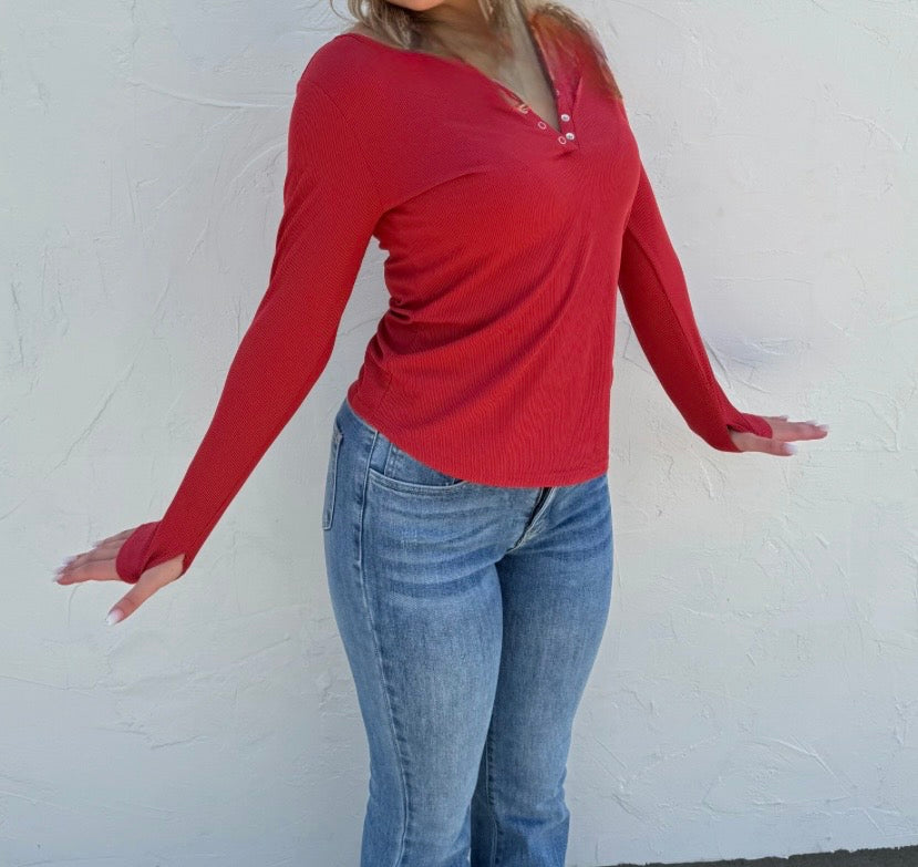 Person wearing a red long-sleeve top and blue jeans against a white background
