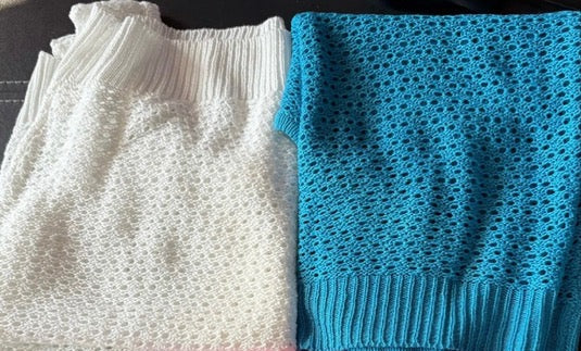 Three knitted items in white, blue, and pink on a dark surface