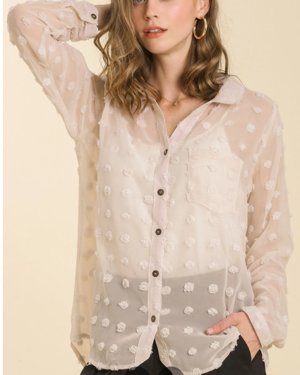 Woman wearing a sheer beige blouse with floral patterns on a light yellow background