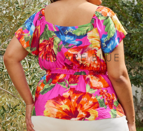 Person wearing a colorful floral top with a blurred background