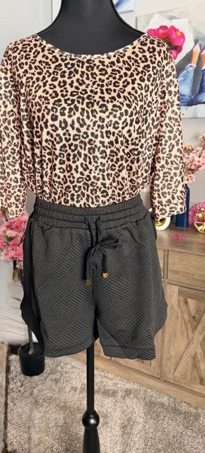 Mannequin wearing a leopard print top and gray shorts with a blurred background