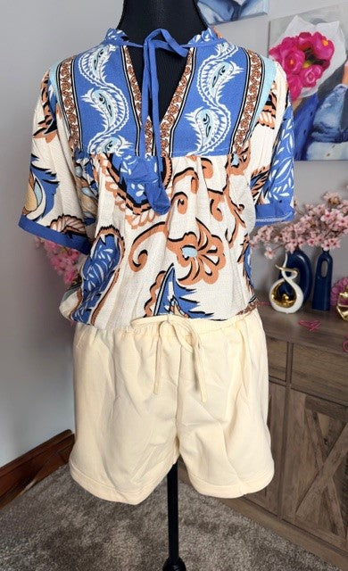 Mannequin wearing a patterned top and beige shorts with a blurred background