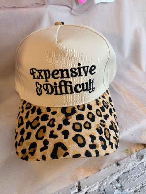 Beige cap with leopard print visor and 'Expensive & Difficult' text on a light background