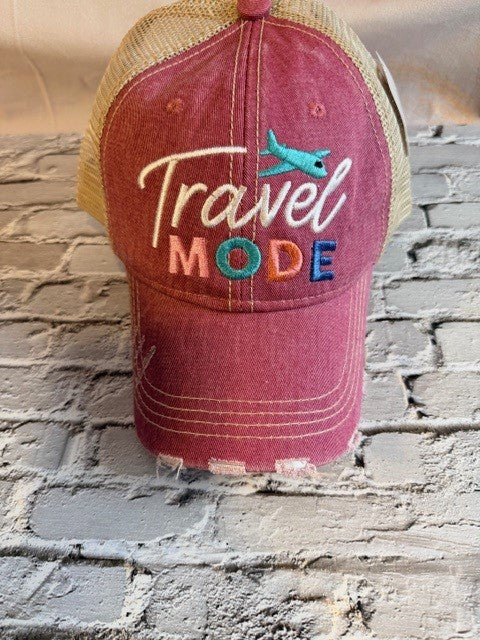 Red cap with 'Travel Mode' text and airplane icon on a stone wall background