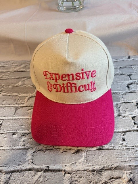 Cap with 'Expensive & Difficult' text on a stone surface