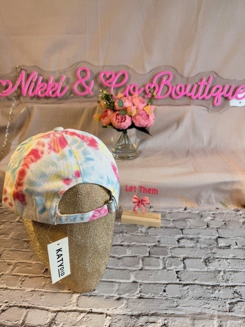 Colorful cap with glittery base on a brick wall background with 'Nikkel & Co Boutique' sign.