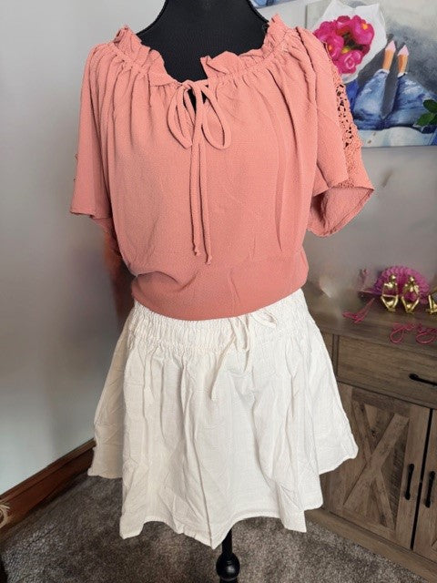 Pink blouse and white skirt on a mannequin against a neutral background